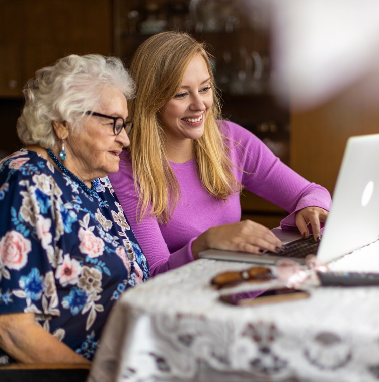 Elderly Woman and middle aged woman looking at a laptop at a dining room table